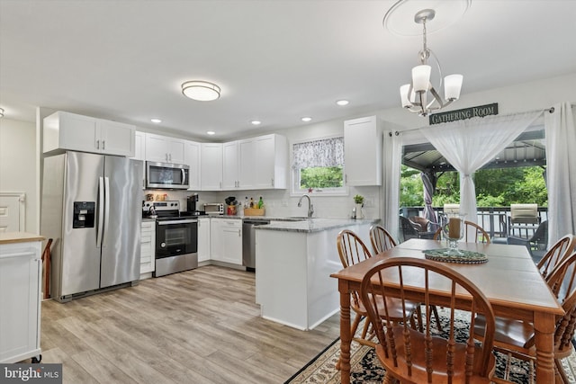 607 Jays Ln, Pottstown, PA 19464 - kitchen with appliances with stainless steel finishes, white cabinets, light wood-style flooring, a peninsula, and pendant lighting
