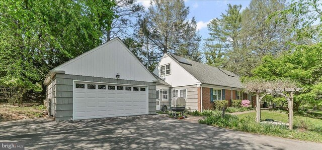 343 Michigan Ave, Swarthmore, PA 19081 - view of front of house featuring brick siding, a garage, and asphalt driveway