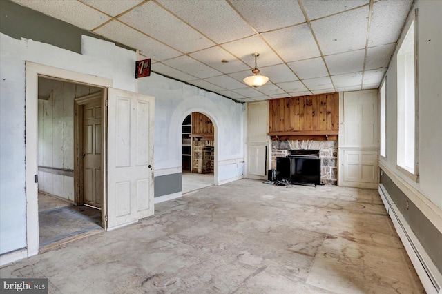 13938 Creek Rd, Willow Hill, PA 17271 - unfurnished living room featuring a baseboard radiator, a stone fireplace, arched walkways, a drop ceiling, and unfinished concrete flooring