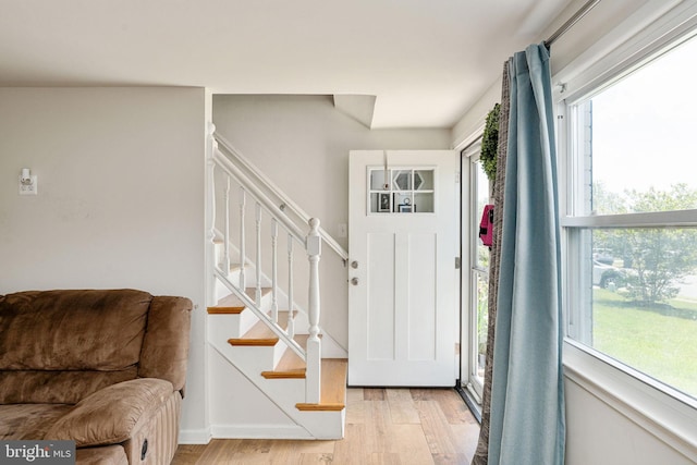 entryway featuring wood finished floors, stairs, and baseboards