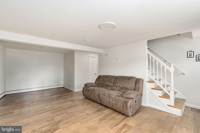 living room featuring light wood-style flooring, stairway, and baseboards