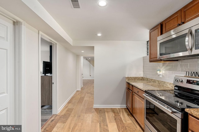 kitchen featuring stainless steel appliances, brown cabinetry, light wood-style flooring, baseboards, and recessed lighting