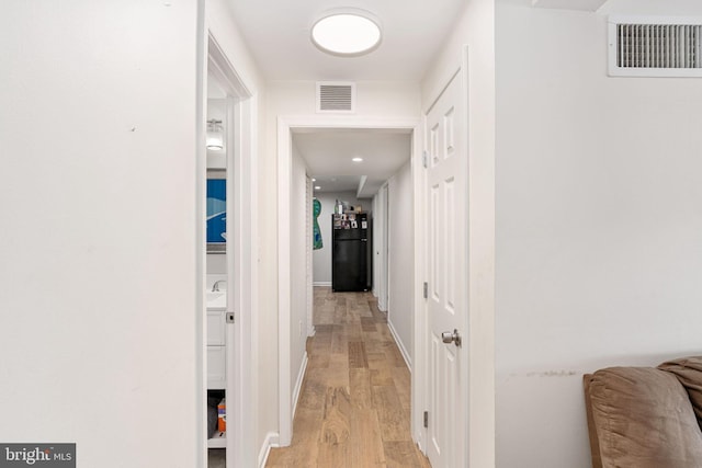 corridor with light wood-style floors and baseboards