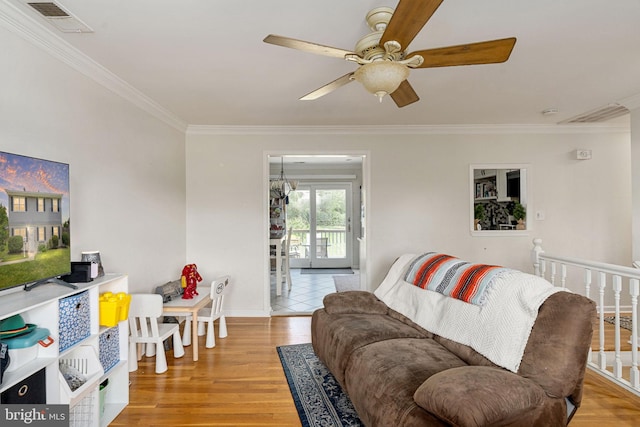 living room with crown molding, a ceiling fan, light wood finished floors, and baseboards