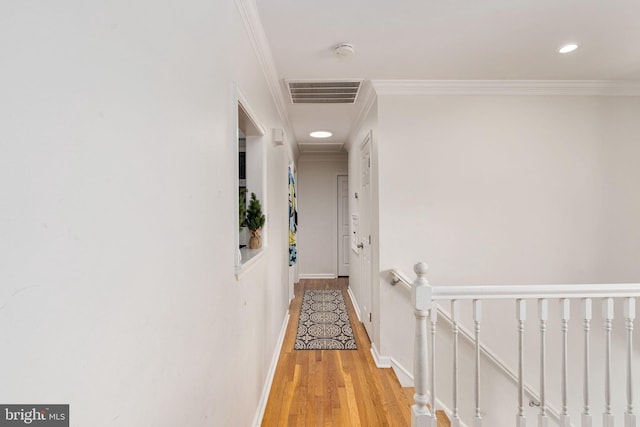 corridor featuring wood finished floors, an upstairs landing, baseboards, ornamental molding, and recessed lighting