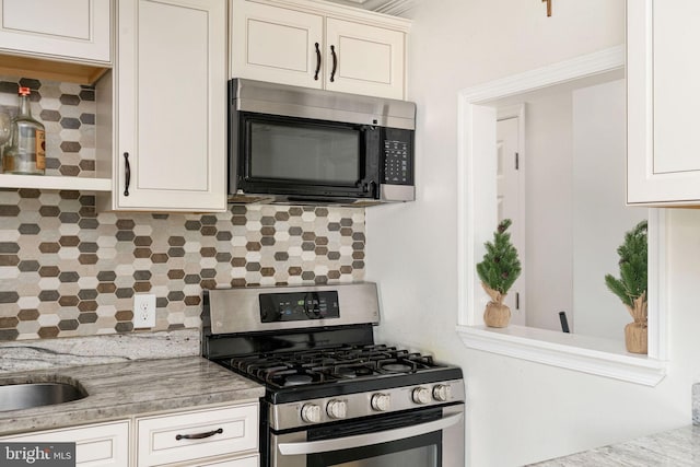 kitchen with appliances with stainless steel finishes, backsplash, white cabinets, and light countertops