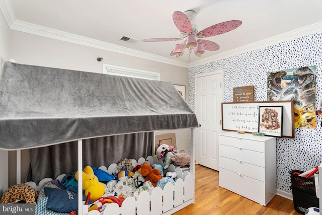 bedroom with crown molding, wood finished floors, wallpapered walls, and baseboards