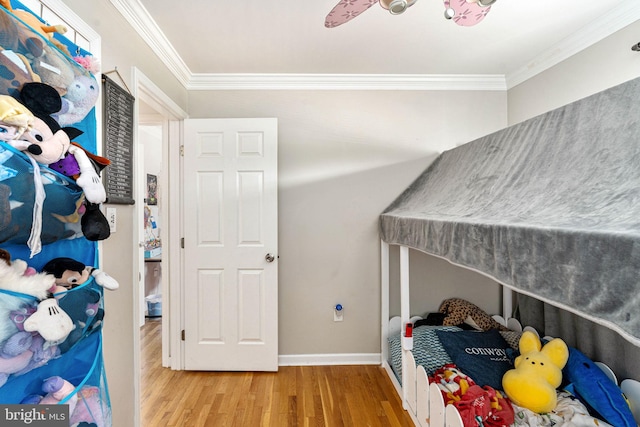 bedroom with wood finished floors, ornamental molding, and baseboards