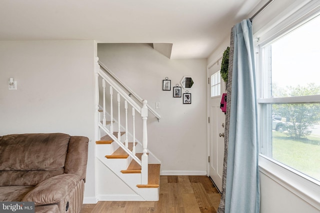 foyer entrance featuring wood finished floors, stairway, and baseboards