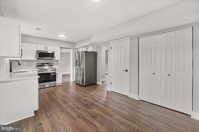 6121 Ducketts Ln, Elkridge, MD 21075 - kitchen featuring stainless steel appliances, a sink, white cabinets, light countertops, and dark wood-type flooring
