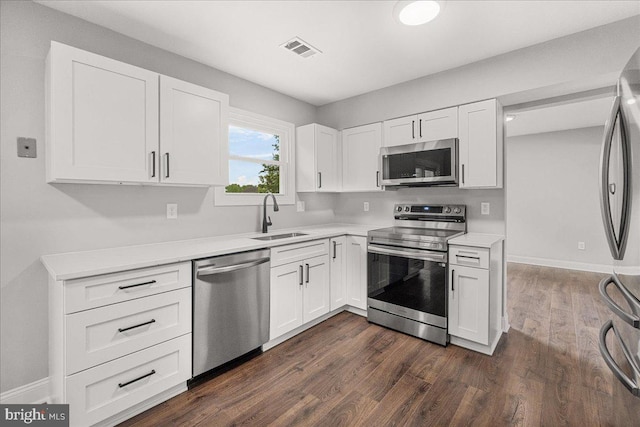 6121 Ducketts Ln, Elkridge, MD 21075 - kitchen with stainless steel appliances, a sink, light countertops, white cabinetry, and dark wood finished floors