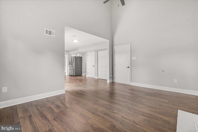6121 Ducketts Ln, Elkridge, MD 21075 - unfurnished living room featuring a towering ceiling, ceiling fan, baseboards, and dark wood-style flooring