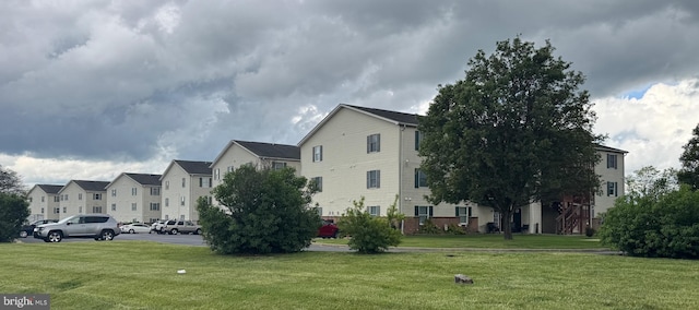 view of property's community with uncovered parking, a residential view, and a lawn