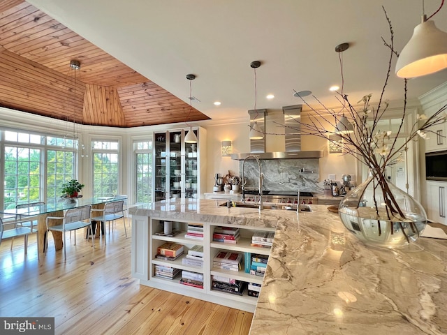 kitchen featuring open shelves, wall chimney range hood, pendant lighting, light stone counters, and recessed lighting