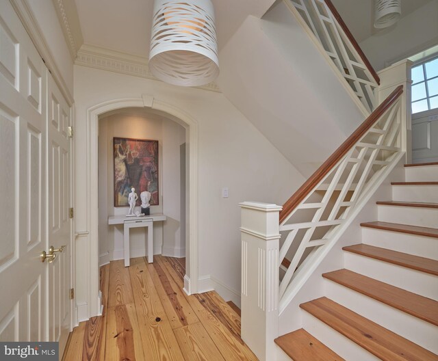 hallway with light wood finished floors, stairway, and baseboards