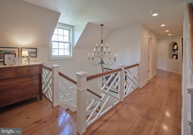hall featuring an upstairs landing, light wood-style floors, a chandelier, vaulted ceiling, and recessed lighting