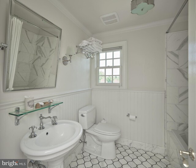 full bathroom featuring wainscoting, toilet, a sink, crown molding, and shower / bath combo