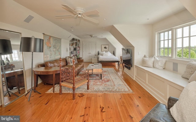 living room with light wood finished floors, a ceiling fan, plenty of natural light, and vaulted ceiling