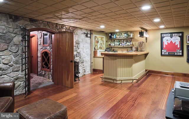 indoor bar featuring baseboards, arched walkways, and wood finished floors