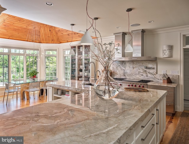 kitchen with a sink, wall chimney range hood, vaulted ceiling, tasteful backsplash, and wooden ceiling
