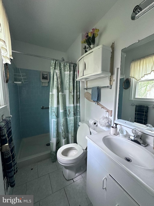 bathroom with vanity, toilet, tile patterned flooring, and a tile shower