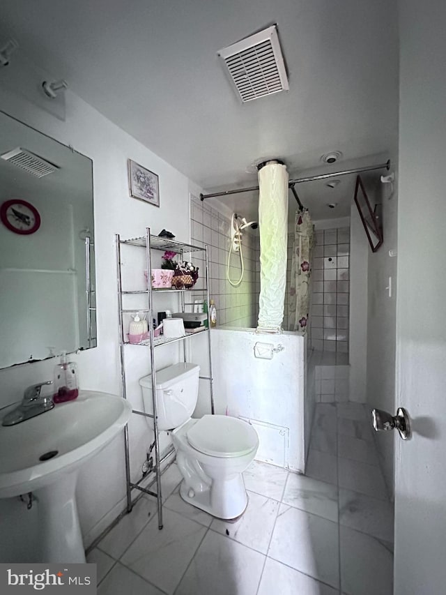 bathroom featuring marble finish floor, toilet, tiled shower / bath, and visible vents