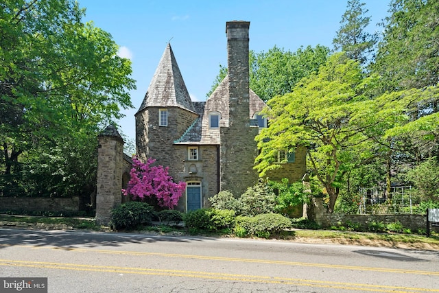 view of front of property with a chimney, a high end roof, and stone siding