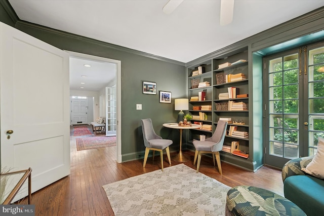 living area featuring ornamental molding, hardwood / wood-style floors, baseboards, and a ceiling fan