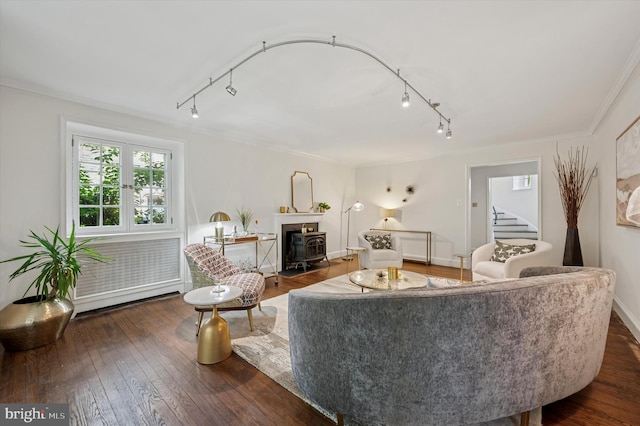 living area with rail lighting, stairs, hardwood / wood-style floors, ornamental molding, and a wood stove