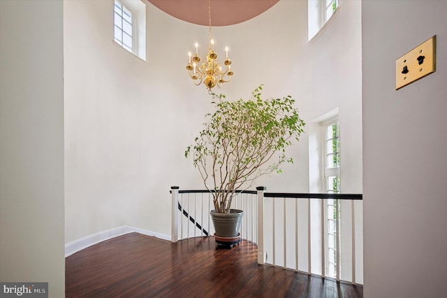 stairway featuring a high ceiling, plenty of natural light, a chandelier, and wood finished floors