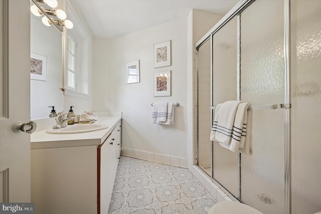 full bathroom featuring vanity, a shower stall, tile patterned floors, and baseboards