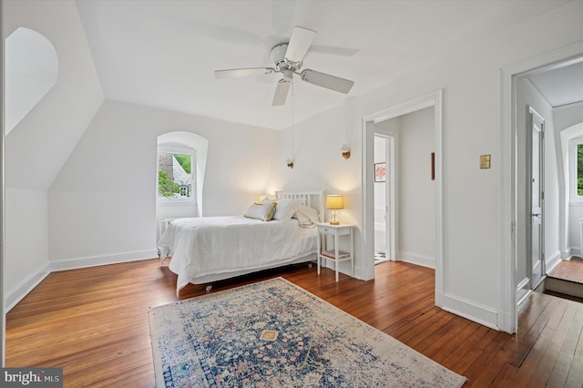 bedroom featuring hardwood / wood-style flooring, attic access, baseboards, lofted ceiling, and a ceiling fan