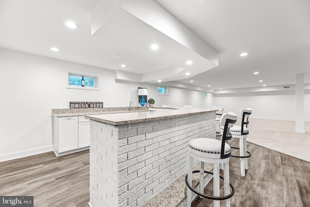 2031 Indian Cir, Saint Leonard, MD 20685 - kitchen with light wood-type flooring, white cabinetry, a kitchen bar, and a kitchen island with sink