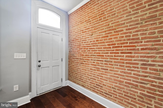 entryway featuring baseboards, dark wood-type flooring, and brick wall