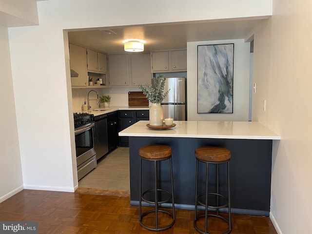 371 Old Forge Xing Unit 371, Devon, PA 19333 - kitchen with appliances with stainless steel finishes, a sink, a peninsula, light countertops, and a kitchen bar