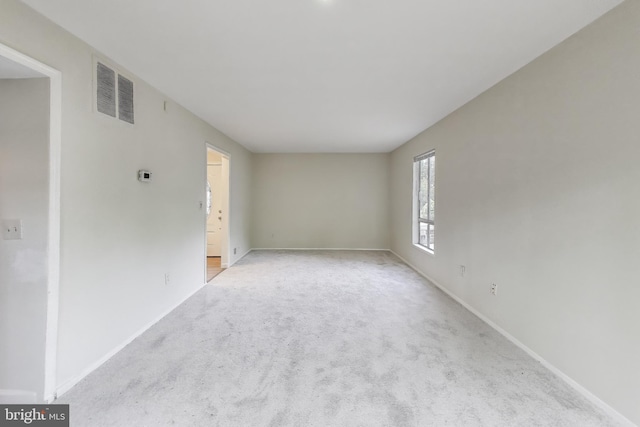spare room featuring light colored carpet and baseboards