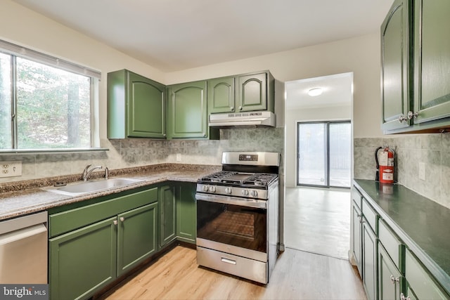 kitchen featuring green cabinets, appliances with stainless steel finishes, under cabinet range hood, a sink, and light wood-style floors