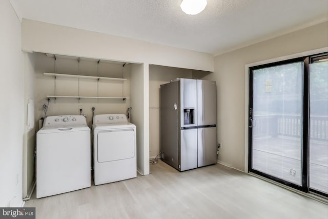 laundry room with light wood-type flooring, washer and dryer, a textured ceiling, and baseboards