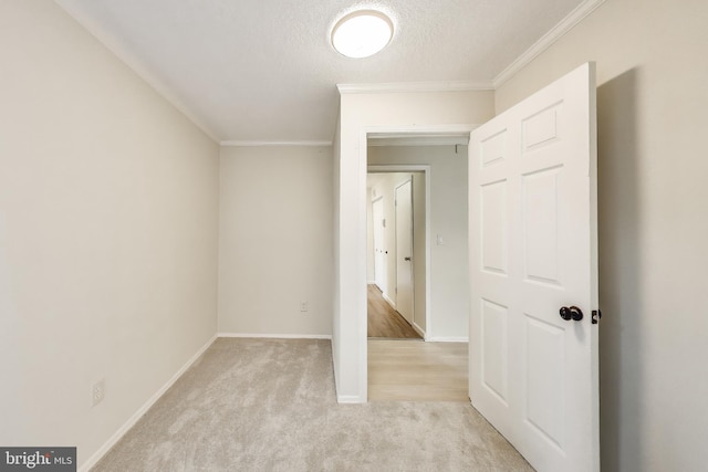 unfurnished bedroom with light carpet, crown molding, a textured ceiling, and baseboards