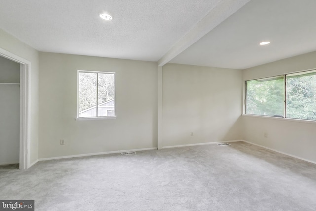 unfurnished bedroom featuring multiple windows, carpet floors, a textured ceiling, baseboards, and recessed lighting