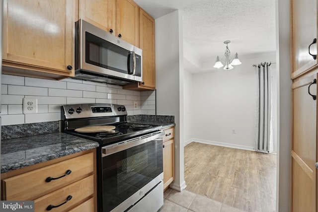 15645 Horseshoe Ln, Woodbridge, VA 22191 - kitchen featuring an inviting chandelier, dark stone countertops, stainless steel appliances, baseboards, and decorative backsplash