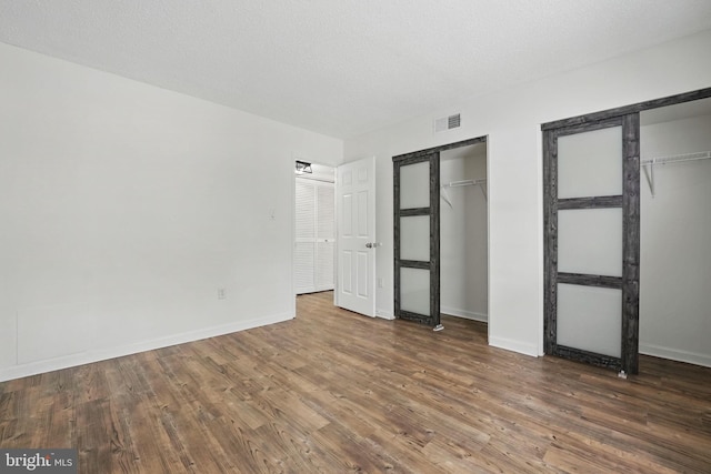15645 Horseshoe Ln, Woodbridge, VA 22191 - unfurnished bedroom featuring baseboards, visible vents, two closets, and wood finished floors