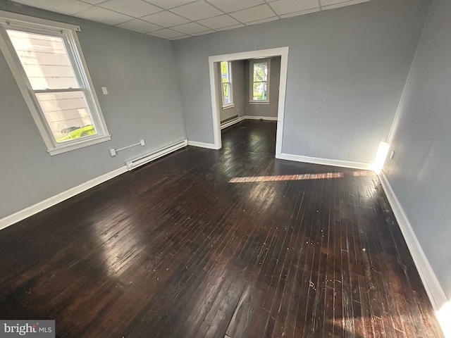 unfurnished room featuring a baseboard heating unit, a drop ceiling, hardwood / wood-style floors, baseboards, and a baseboard radiator