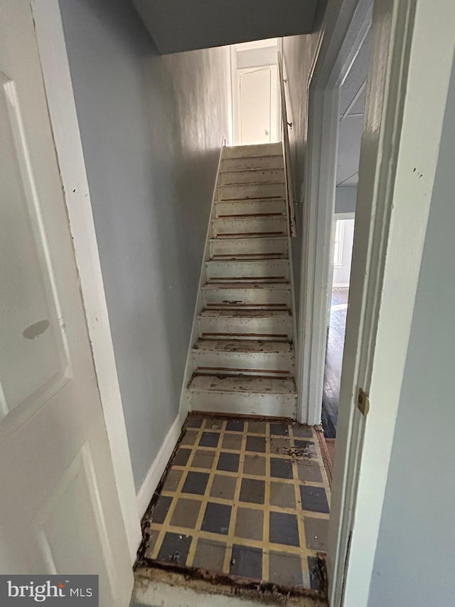 stairway with baseboards and tile patterned floors
