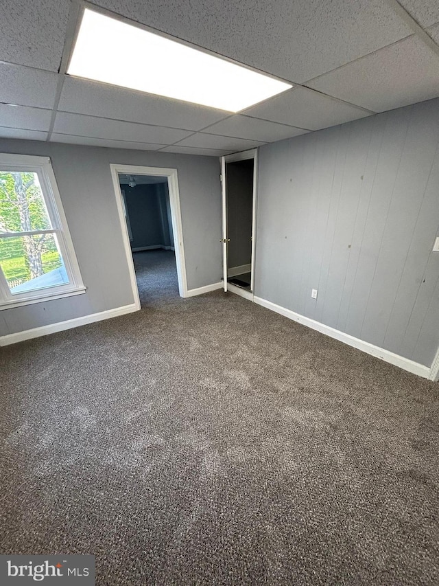 unfurnished room featuring carpet flooring, a paneled ceiling, and baseboards