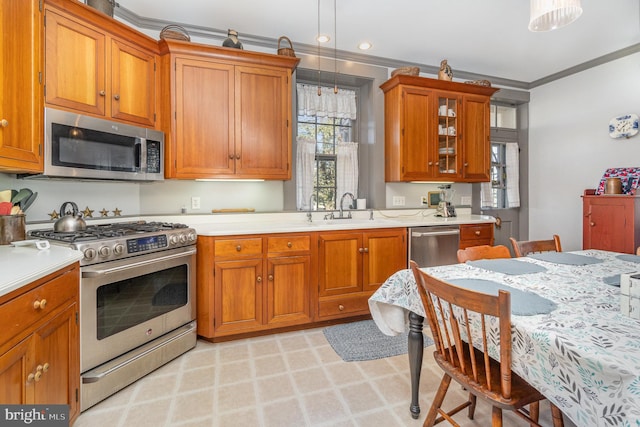 kitchen with a sink, ornamental molding, stainless steel appliances, and light countertops