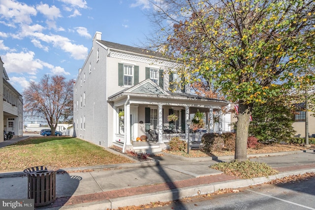 view of front of home featuring a chimney, a front yard, and covered porch