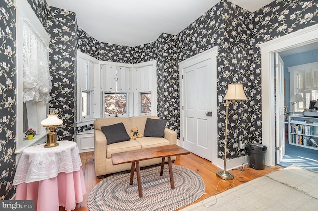 living area with baseboards, wallpapered walls, and wood finished floors