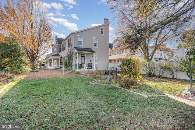 back of house featuring a yard, fence, and a chimney
