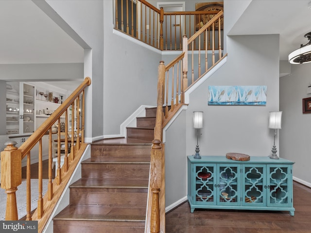 33759 Bay Ridge Ln, Lewes, DE 19958 - staircase featuring baseboards, wood finished floors, and a towering ceiling